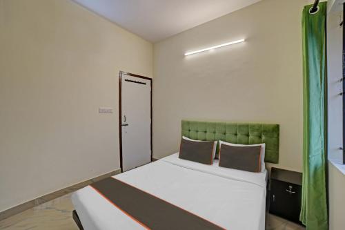 a small bedroom with a bed with a green headboard at Collection O Sunshine Studio Rooms in Bangalore