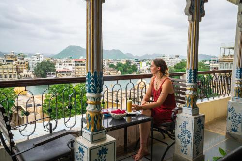 a woman sitting at a table on a balcony at Dreamyard Udaipur in Udaipur