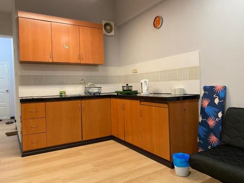 a kitchen with wooden cabinets and a black counter top at KK City Api Api Apartment beside Centre Point by JR Homestay in Kota Kinabalu