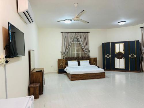 a bedroom with a bed and a flat screen tv at البيت الأبيض للشقق المفروشة White House in Salalah