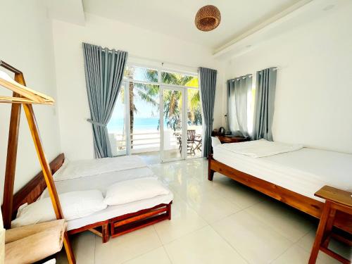 two beds in a room with a view of the ocean at Lucky Spot Beach Bungalow in Song Cau