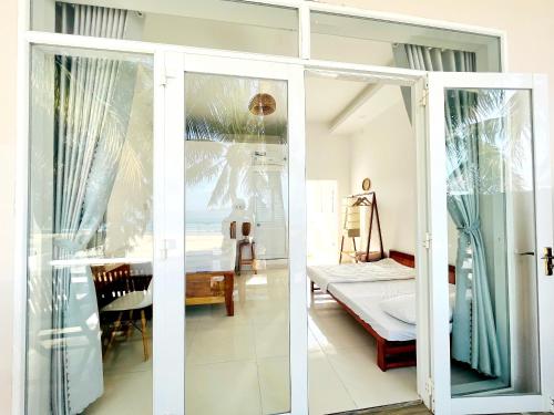 a living room with a sliding glass door and a bedroom at Lucky Spot Beach Bungalow in Song Cau