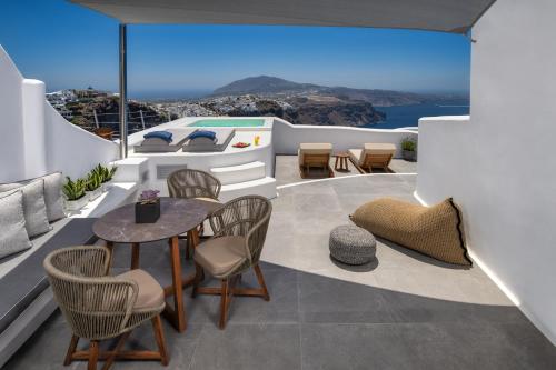 a patio with a table and chairs on a balcony at Eteoro Suites in Imerovigli