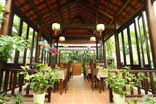 un restaurante con mesas, sillas y macetas en Hoi An Holiday Villa, en Hoi An