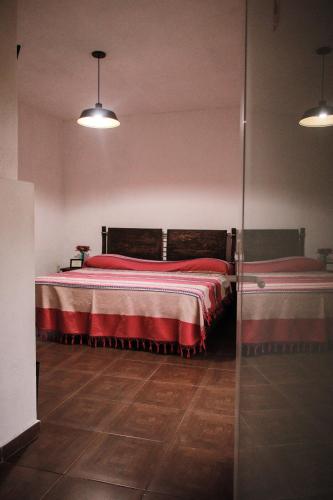 a bedroom with two beds with red sheets and wooden floors at Hospedaje Casa Teotleco in Tepoztlán