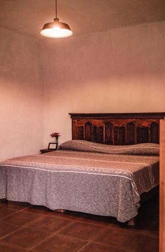 a bedroom with a large bed with a wooden headboard at Hospedaje Casa Teotleco in Tepoztlán