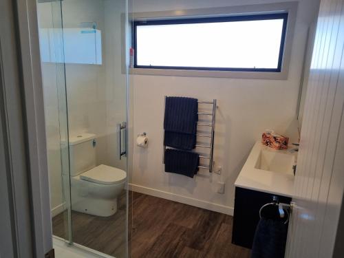 a bathroom with a toilet and a glass shower at Jafa's Holiday House in Lawrence