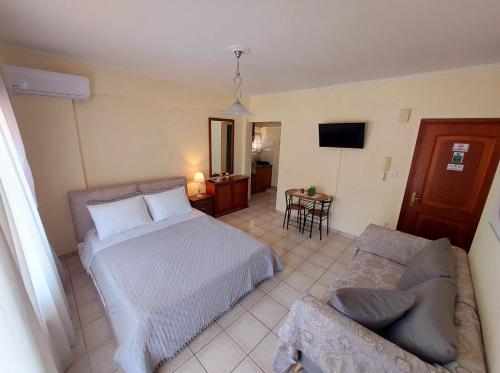 1 dormitorio con cama, sofá y TV en Eleni's Apartments Igoumenitsa -- Γκαρσονιέρα 1ου ορόφου επιπλωμένη, εξοπλισμένη, en Igoumenitsa