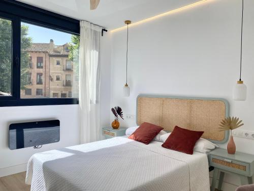 a bedroom with a white bed with red pillows and a window at AM I Segovia VUT in Segovia