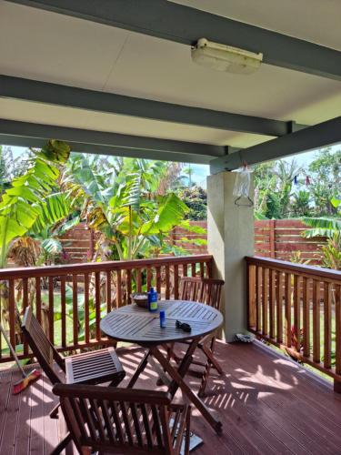 a patio with a table and chairs on a deck at Dominic's Beach Bungalow in Muri