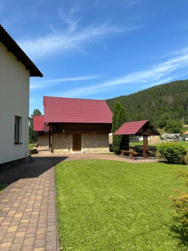 a house with a red roof and a grass yard at Садиба "Джерело" in Yaremche