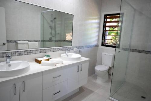 a bathroom with two sinks and a shower and a toilet at Fabulous 2 bedroom with private pool in Airlie Beach