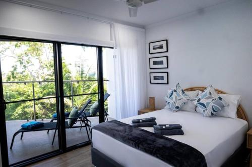 a bedroom with a large white bed and a balcony at Fabulous 2 bedroom with private pool in Airlie Beach