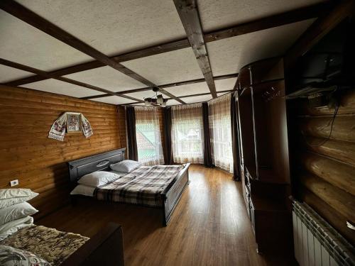 a bedroom with a bed in a room with wooden walls at Sadyba u Anastasijky in Synevyr