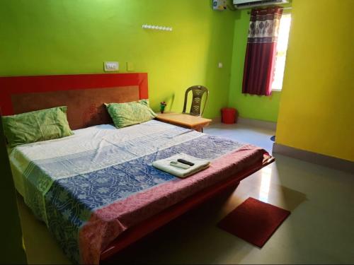 ein Schlafzimmer mit einem Bett mit grünen Wänden in der Unterkunft Goroomgo Sun Plaza Lodge konark in Konark