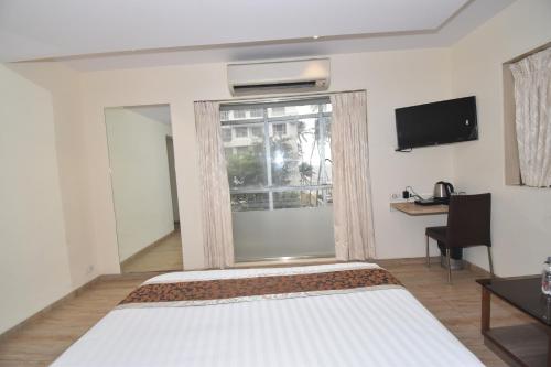 a bedroom with a bed and a window and a desk at Hotel Atlantic in Mumbai
