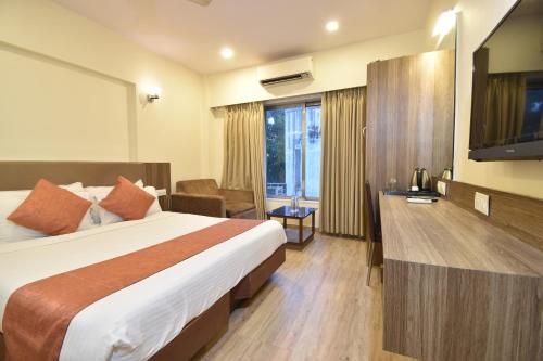 ムンバイにあるHotel Atlanticのベッドとテレビが備わるホテルルームです。