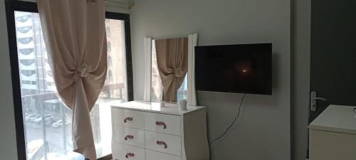um quarto com uma cómoda, uma televisão e uma janela em Private Room in shared Apartment em Abu Dhabi
