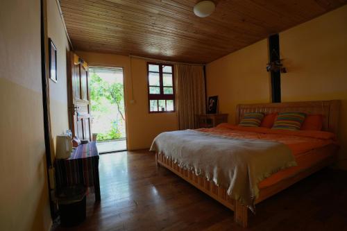 ein Schlafzimmer mit einem Bett mit orangefarbener Bettwäsche und einem Fenster in der Unterkunft Kevin's Trekker Inn in Shangri-La