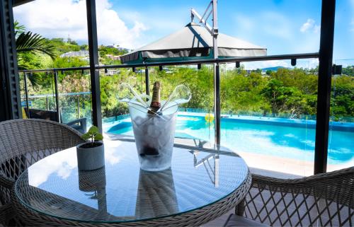 a glass table with a drink on it next to a pool at Fabulous 2 bedroom with private pool in Airlie Beach