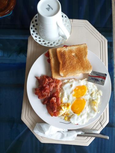 un plato de desayuno con huevos tocino y tostadas en Home Sweetie Homestay & Bunkbeds, en Moalboal