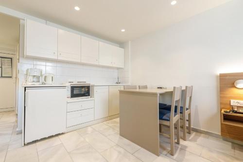 a kitchen with white cabinets and a table and chairs at Kostakis Beach in Gerani Chanion