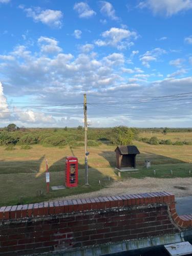 a red phone booth and a building in a field at New Forest View in Beaulieu