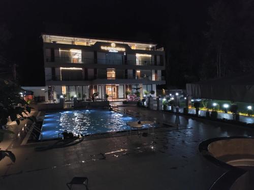 a large building with a swimming pool at night at Green Icon Hotels & Resorts in Kandogal
