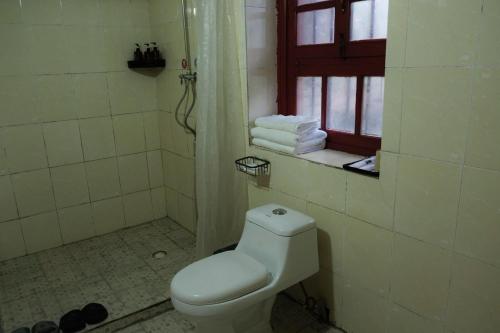 a bathroom with a toilet and a window and towels at Kevin's Trekker Inn in Shangri-La