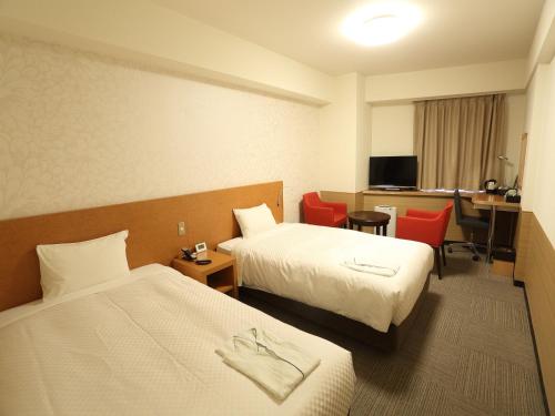 a hotel room with two beds and a desk at Hotel Century Art in Fukuoka