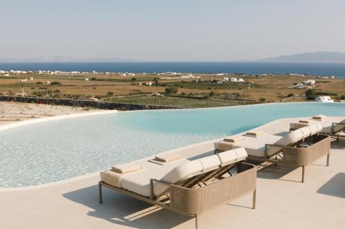 einen Pool mit Stühlen und das Meer im Hintergrund in der Unterkunft Elysian Retreat in Oia