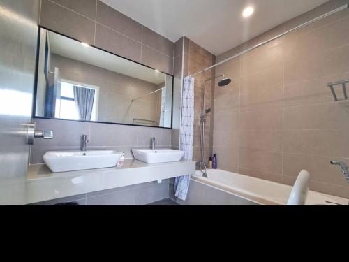 y baño con 2 lavabos, bañera y espejo. en Lion Home, en Seri Kembangan