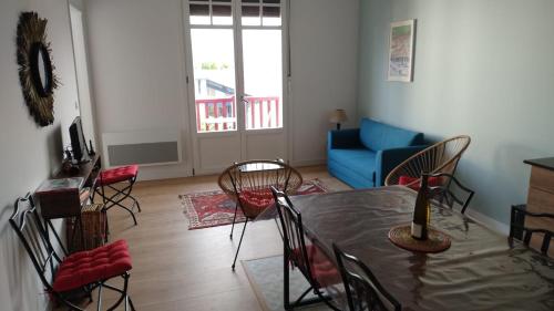 a living room with a table and chairs and a blue couch at Hendaye plage, Résidence Eskualduna A in Hendaye