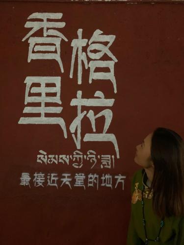 a woman standing in front of a wall with writing at Kevin's Trekker Inn in Shangri-La