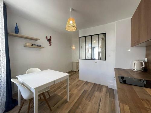 une cuisine blanche avec une table et des chaises dans une pièce dans l'établissement Charmante maison au village, à Gruissan