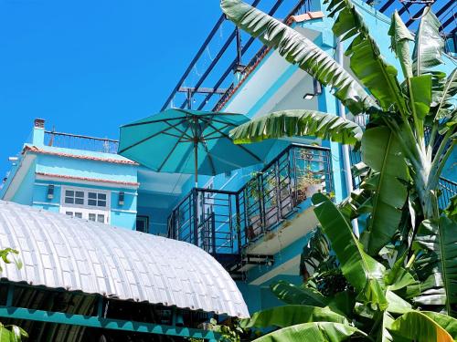 un edificio azul con balcón y sombrilla en Quy Phuong - Homestay, en Tân Hiệp