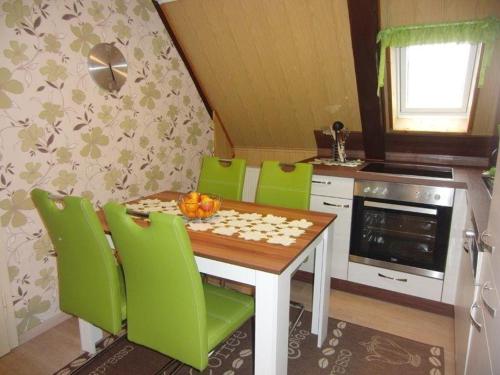 uma cozinha com uma mesa de jantar e cadeiras verdes em Ferienwohnung-Ritscher-in-Lichtenhain-1 em Lichtenhain