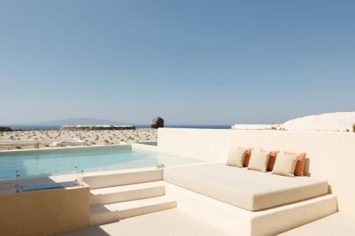 białą kanapę siedzącą obok basenu w obiekcie Elysian Retreat w mieście Oia