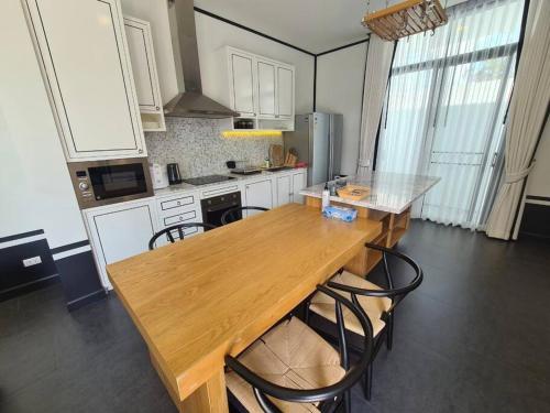 a kitchen with a wooden table and some chairs at Full Moon现代豪华三卧室泳池别墅 查龙海滩 500 米 查龙码头 普吉大佛 拉威海鲜 in Chalong 