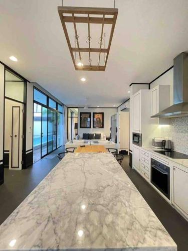 a large kitchen with a large table in the middle at Full Moon现代豪华三卧室泳池别墅 查龙海滩 500 米 查龙码头 普吉大佛 拉威海鲜 in Chalong 