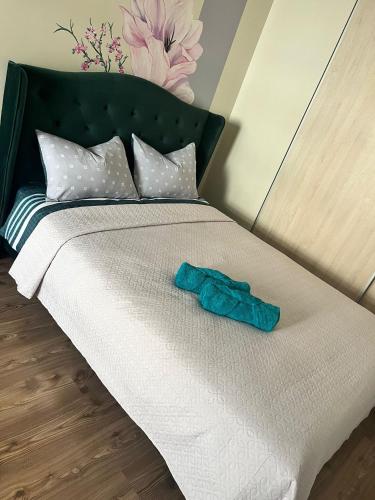 ein weißes Bett mit einem grünen Kopfteil und einem Bademantel. in der Unterkunft Our Little World in Liepāja