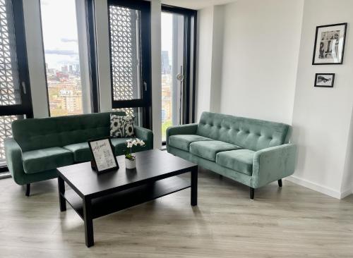 a living room with two green couches and a coffee table at Manhattan Pad in London