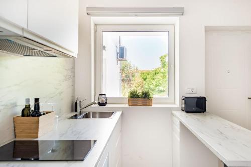 een witte keuken met een wastafel en een raam bij New beautiful studio, private terrace-Hvar town in Hvar