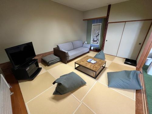 a living room with a couch and a tv at Sapporo's Secret Onsen Sanctuary Marukoma Onsen Ryokan in Chitose