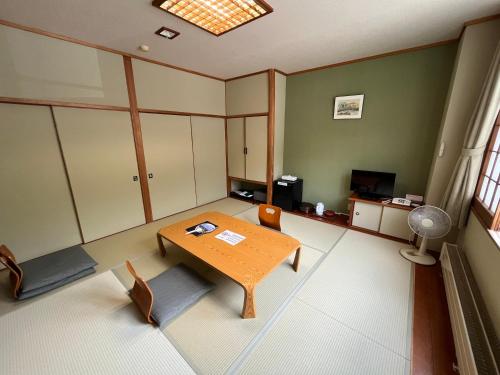 a living room with a wooden table and chairs at Sapporo's Secret Onsen Sanctuary Marukoma Onsen Ryokan in Chitose