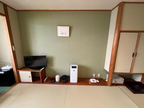 a room with a counter with a computer and a television at Sapporo's Secret Onsen Sanctuary Marukoma Onsen Ryokan in Chitose