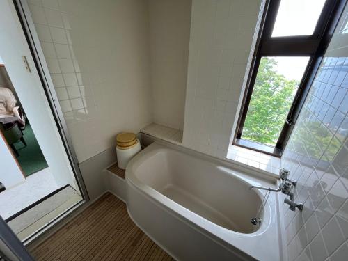 a white bath tub in a bathroom with a window at Sapporo's Secret Onsen Sanctuary Marukoma Onsen Ryokan in Chitose