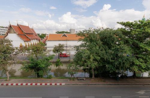 a white building with trees in front of a street at Shapel Hostel and Cafe in Chiang Mai
