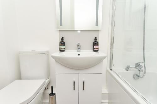 a white bathroom with a sink and a shower at Stunning 3 Bed Apt With Countryside Views & Parking - Ideal For Families, Groups & Business Stays - Close To Ventnor, Shanklin & Sandown in Ventnor