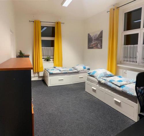 two beds in a room with yellow curtains at Ubytovanie v centre FREE PARKING in Martin